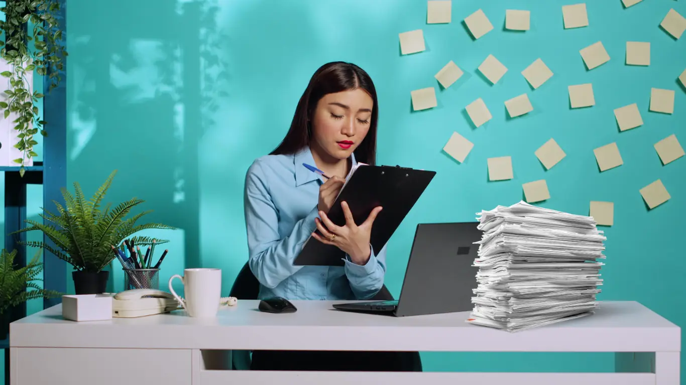 A stack of paperwork beside a laptop — the refreshed document set assembled at month 21 of temporary residency