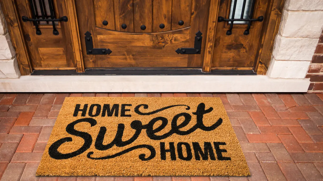 A 'Home Sweet Home' doormat at a wooden front door — the homecoming feeling at the end of the conversion journey
